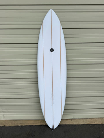 White surfboard leaning against a gray garage door