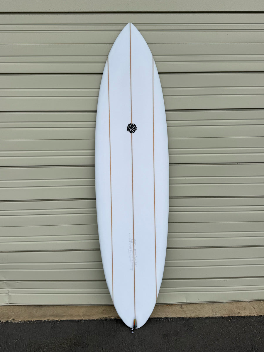 White surfboard leaning against a gray garage door