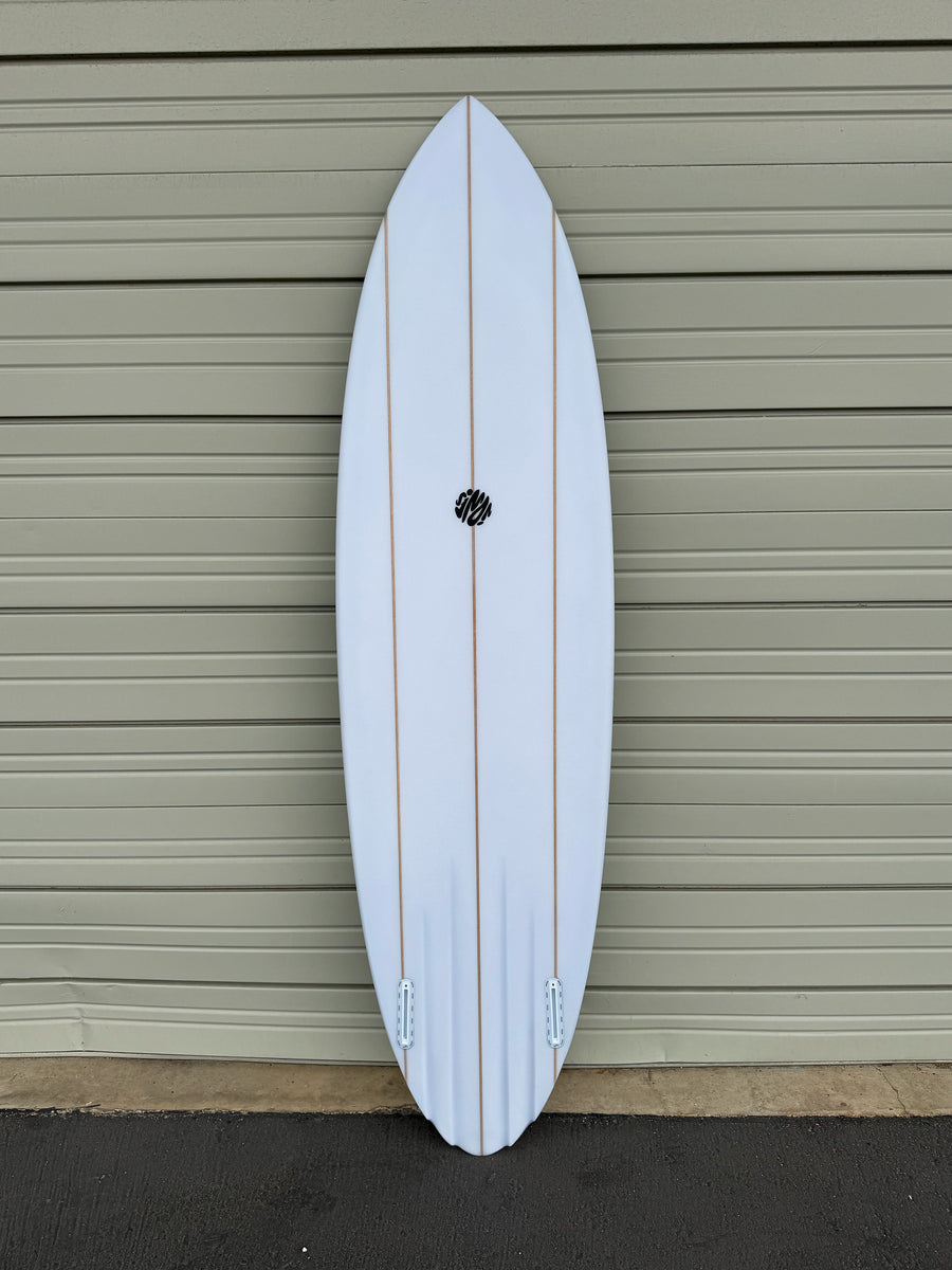 White surfboard with a black logo against a beige garage door